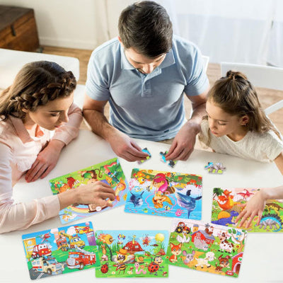 adulte et enfants assemblant plusieurs puzzles en bois illustrés autour d’une table
