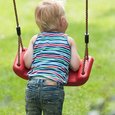 enfant qui joue sur une balançoire colorée dans le jardin
